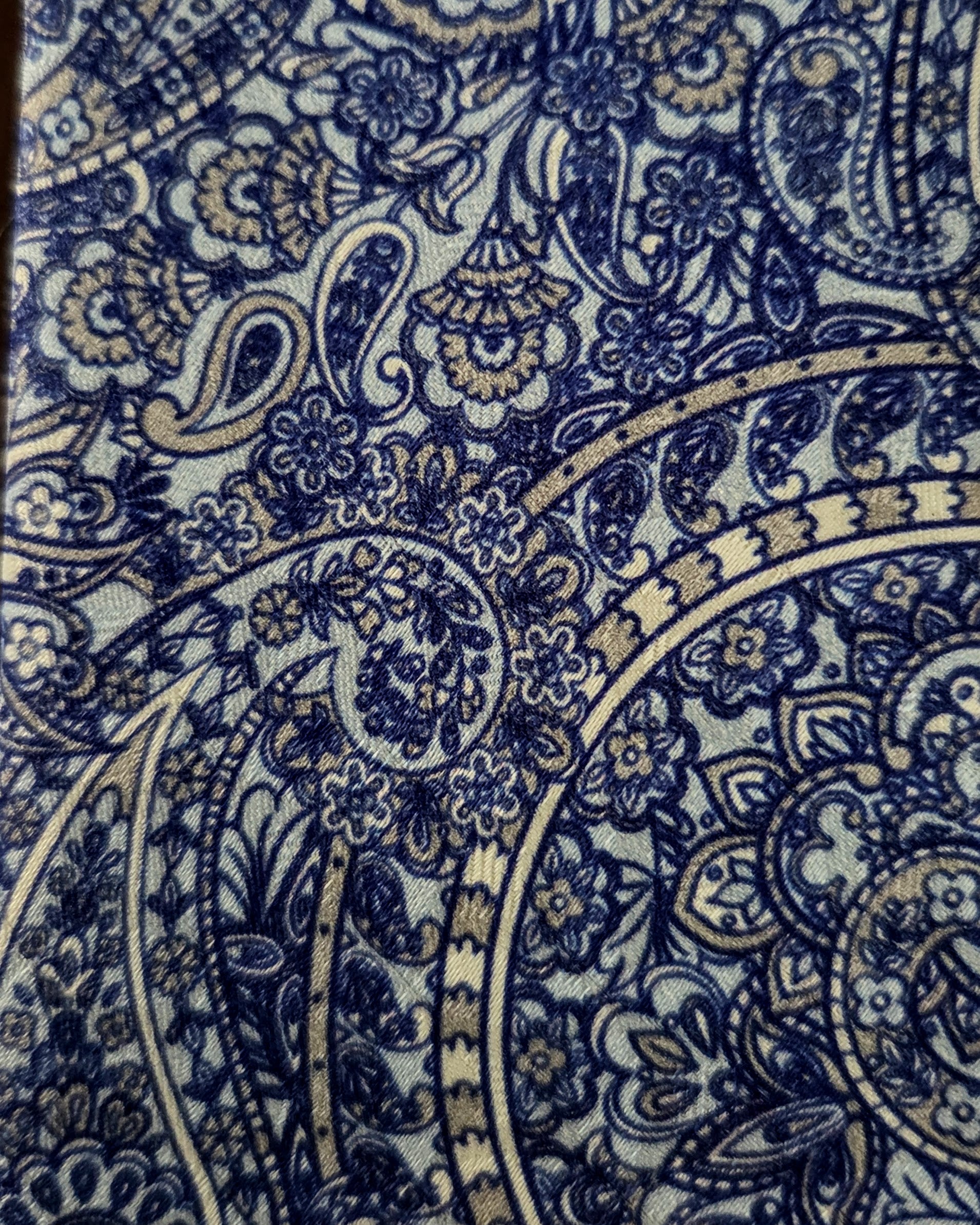 A close-up of a fabric or wallpaper pattern featuring an intricate navy blue and gray paisley and floral design.