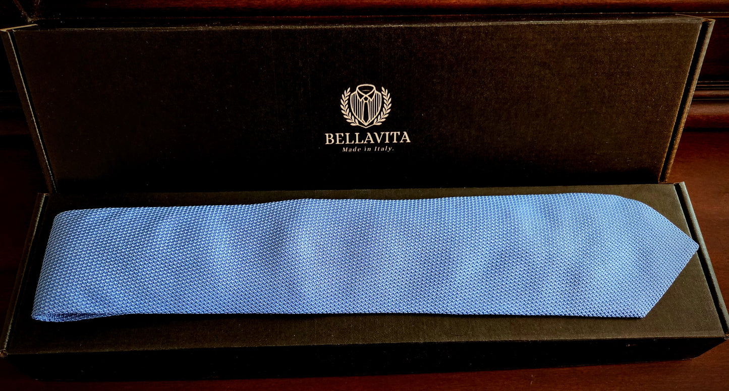 A light blue textured necktie presented inside an open black Bellavita gift box on a dark wooden surface.