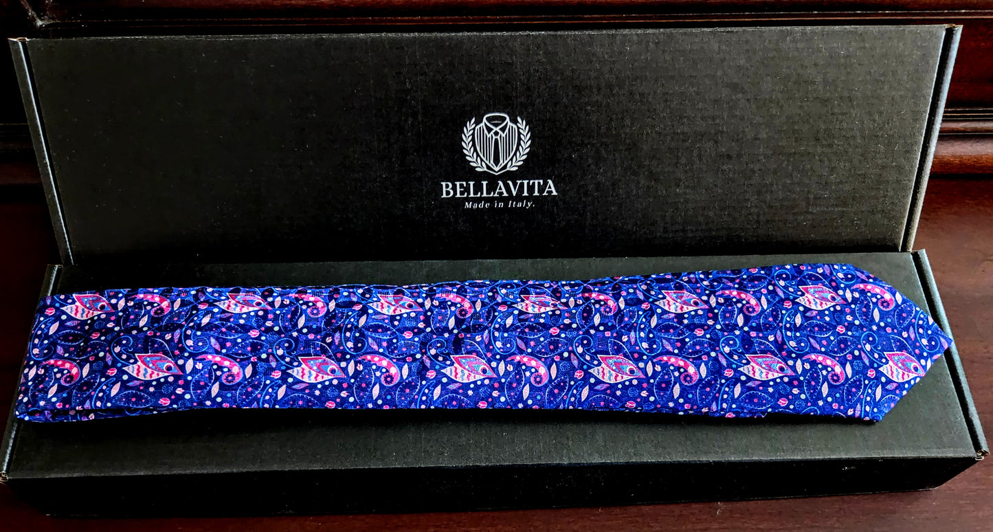 A blue patterned necktie with pink and purple paisley motifs, presented inside an open black Bellavita gift box on a dark wooden surface.