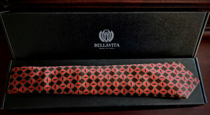 A Bellavita necktie with a red and black geometric pattern, presented inside its black branded gift box on a dark wooden surface.