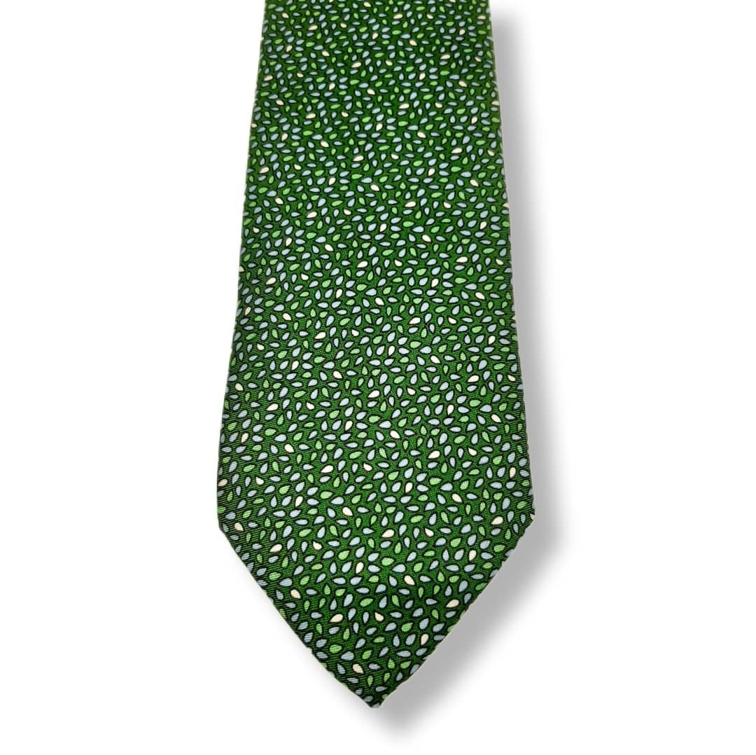 A green necktie with a dense pattern of small white and light green leaf-like motifs, shown against a plain white background with a soft drop shadow.