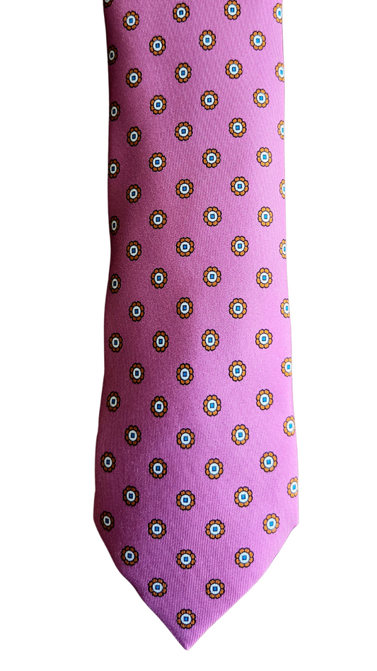 A pink necktie with a repeating pattern of small white and green circular medallions, shown against a plain white background.