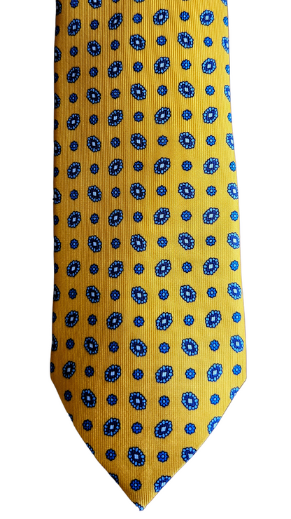 A yellow necktie with a repeating blue and white geometric pattern, shown flat against a plain white background.